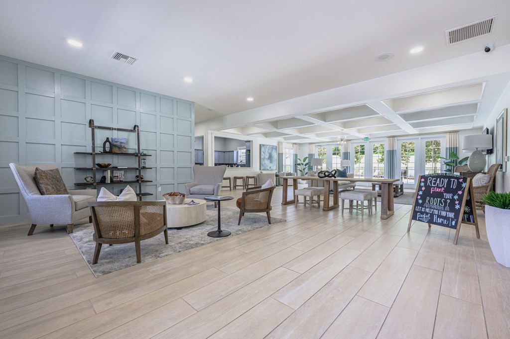A room with wooden floors and a variety of seating options.at Spring Creek Apartments, Crestview, 32536