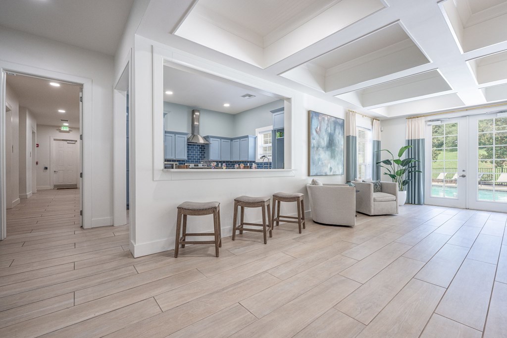 A spacious living room with a kitchen in the background and a dining table with chairs in the foregroundat Spring Creek Apartments, Crestview.