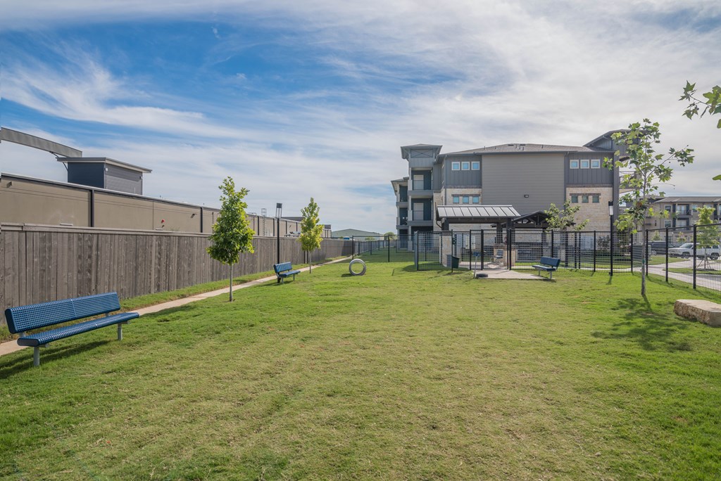 A grassy area with benches and a building in the background.