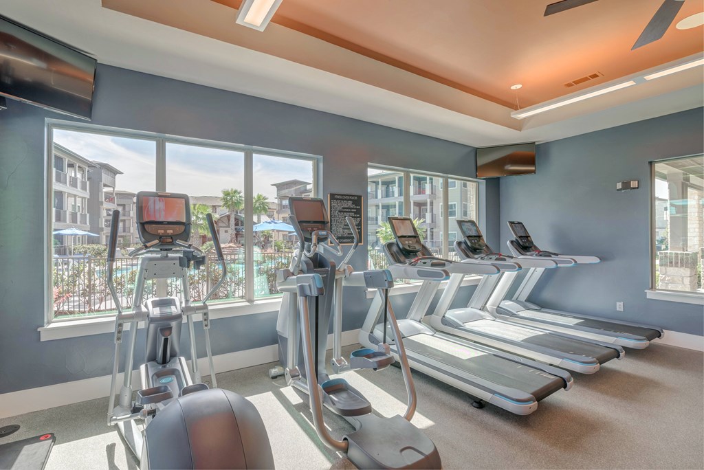 A gym with treadmills, elliptical machines, and a rowing machine.