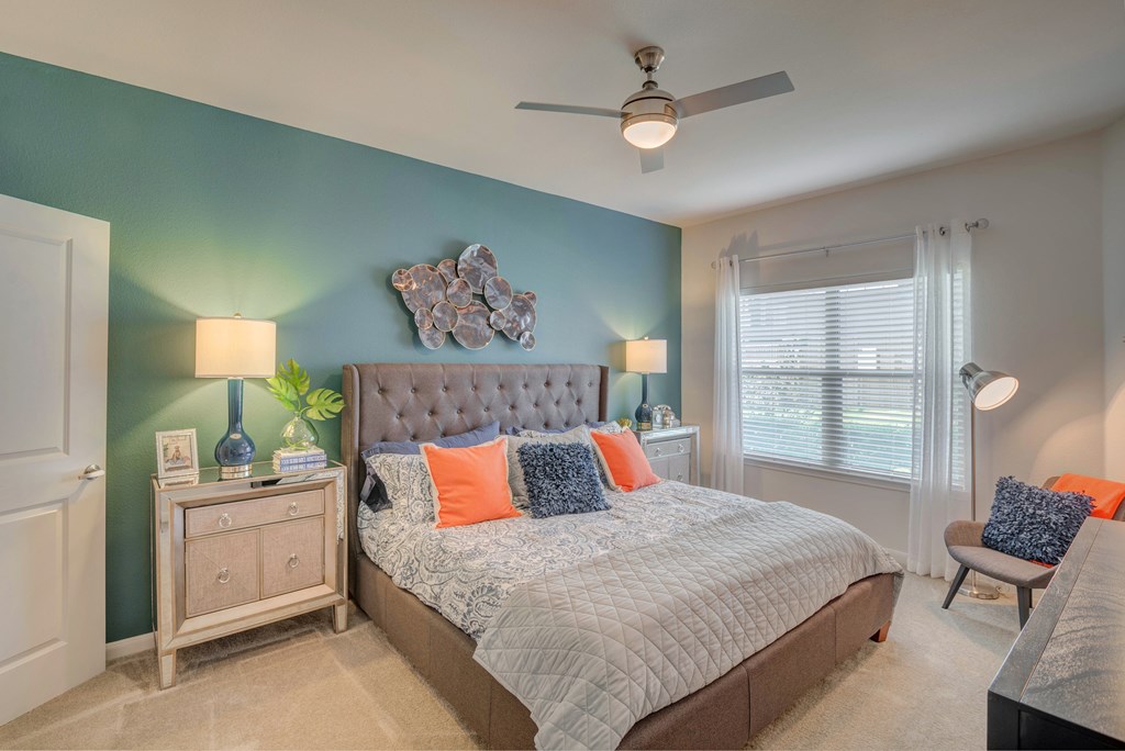 A bedroom with a bed, nightstand, and a ceiling fan.