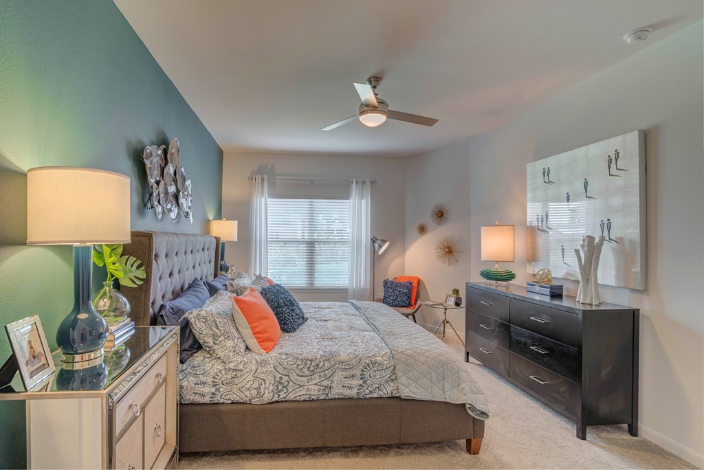 A bedroom with a bed, dresser, and ceiling fan.