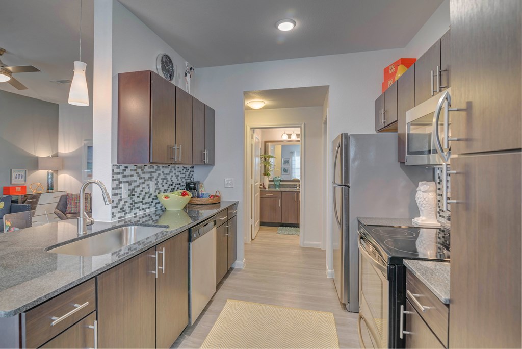 A kitchen with a refrigerator, sink, and cabinets.