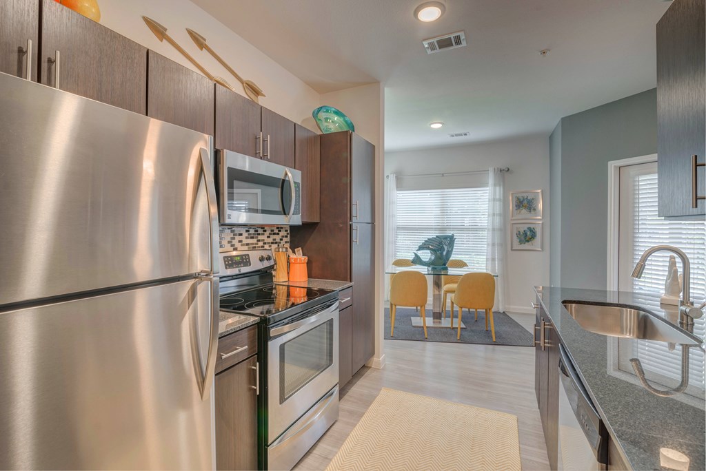 A modern kitchen with stainless steel appliances and a dining area with a table and chairs.