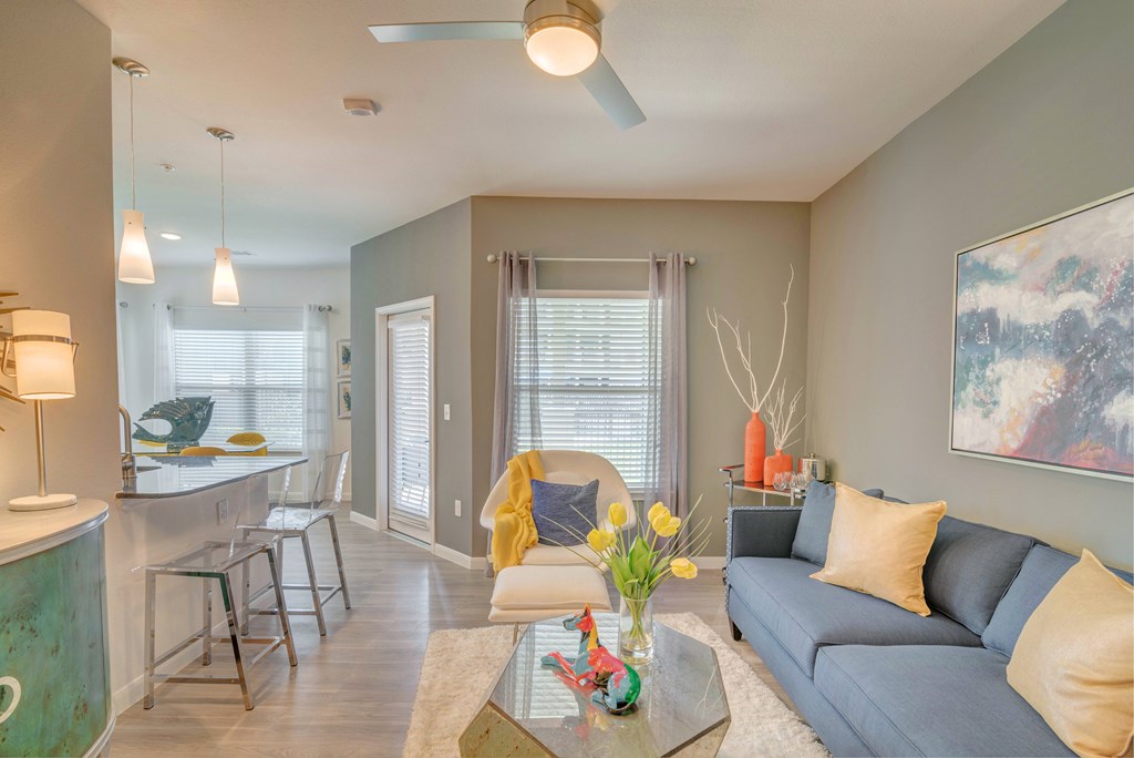 A living room with a grey couch and a yellow throw pillow.