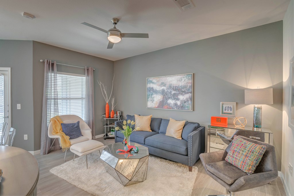 A living room with a grey couch, a coffee table, and a ceiling fan.