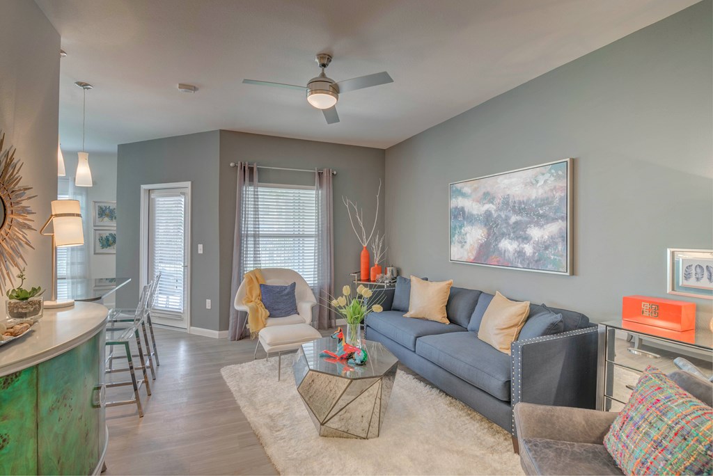 A living room with a grey couch and a painting on the wall.