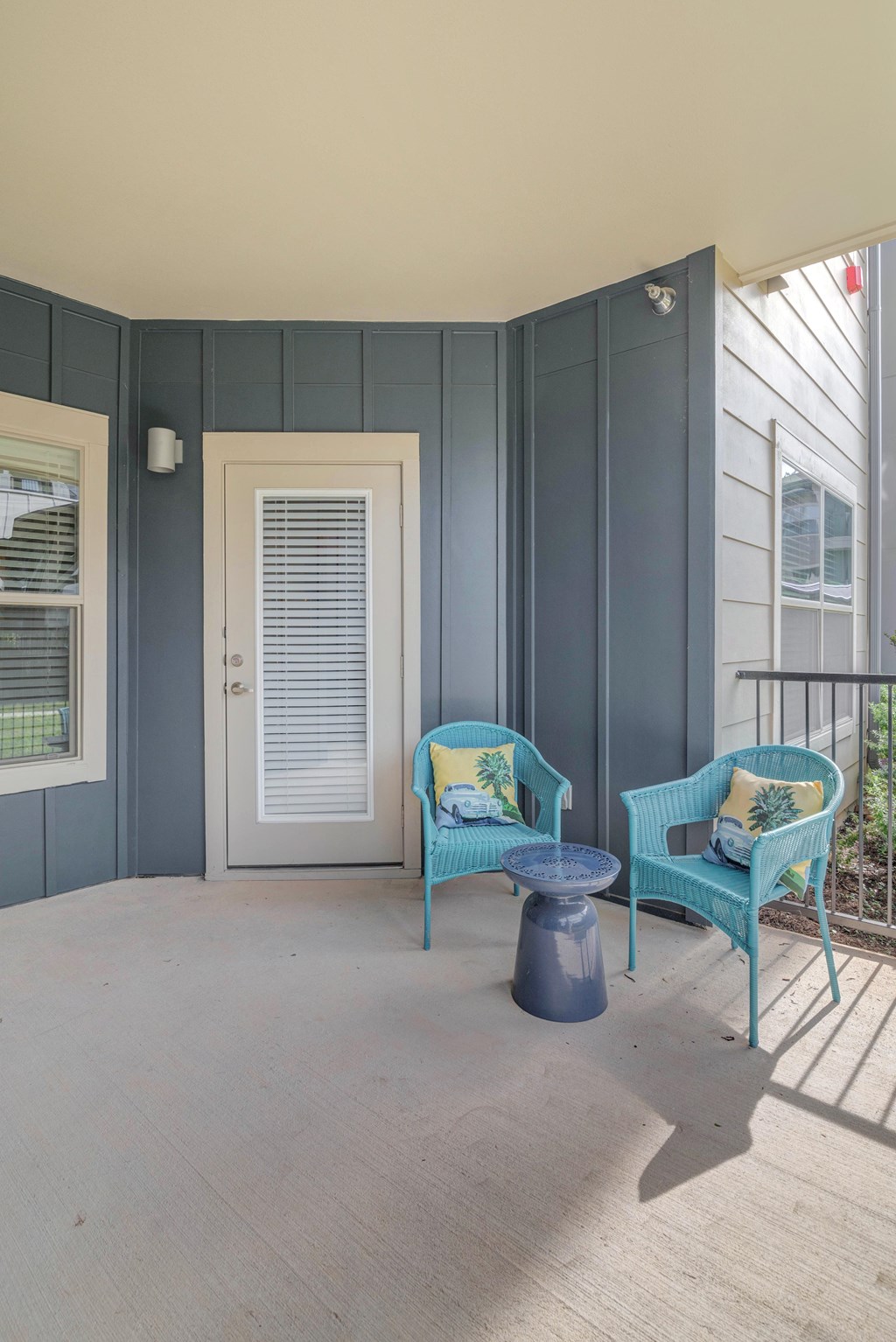 A balcony with a blue chair and a matching ottoman.