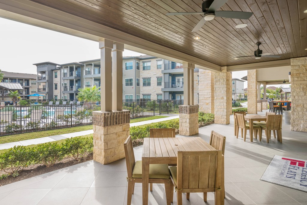 A patio with a table and chairs overlooking a parking lot.