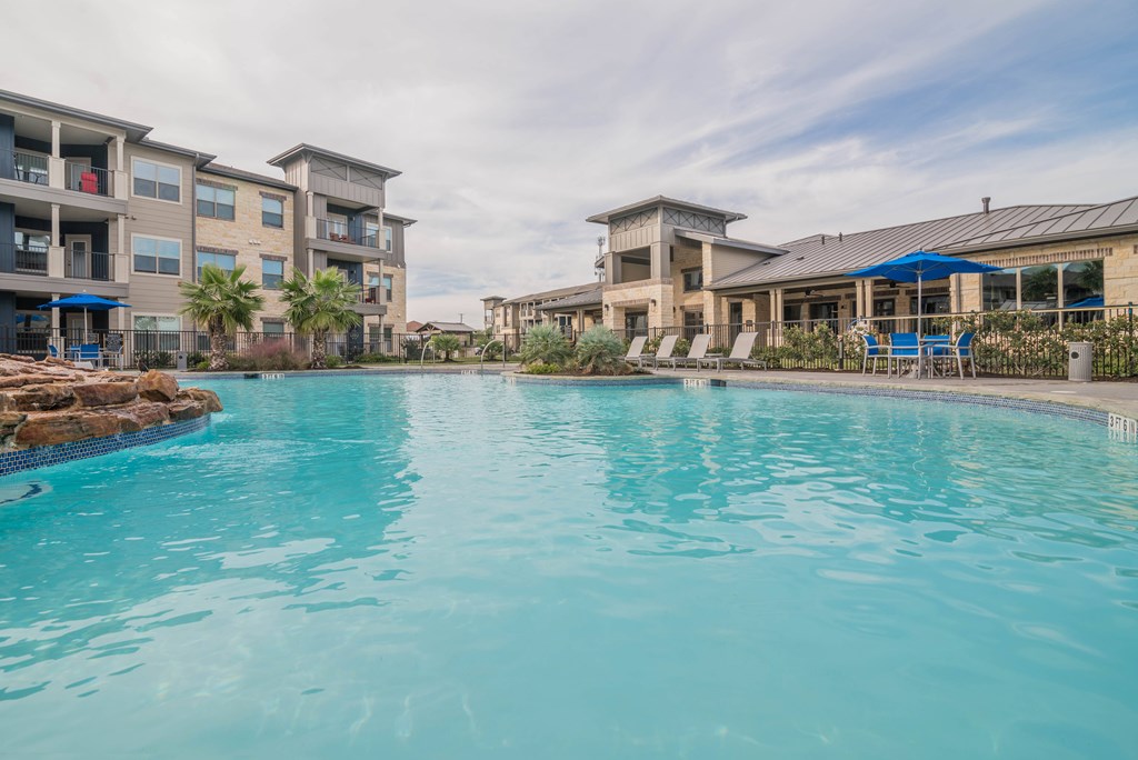 A swimming pool in front of a building with a blue sky in the background.