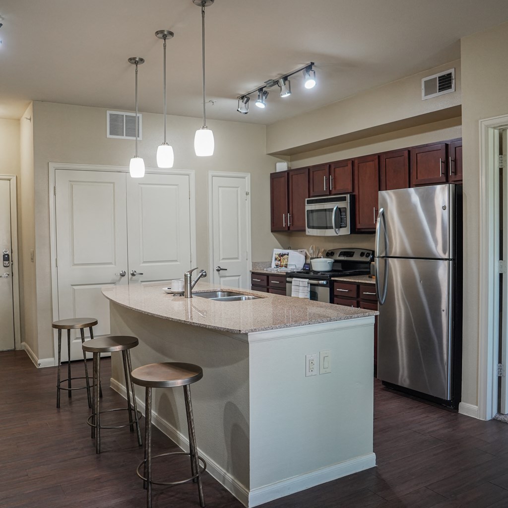 a kitchen with an island with stools and a stainless steel refrigerator at Platinum Castle Hills, Lewisville, 75056