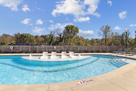 A pool with a fence and trees in the background.