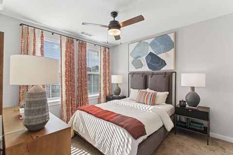 A bedroom with a bed, nightstands, and a ceiling fan.