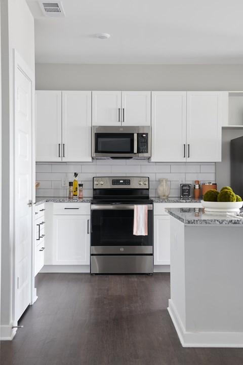 A kitchen with white cabinets and a marble countertop.