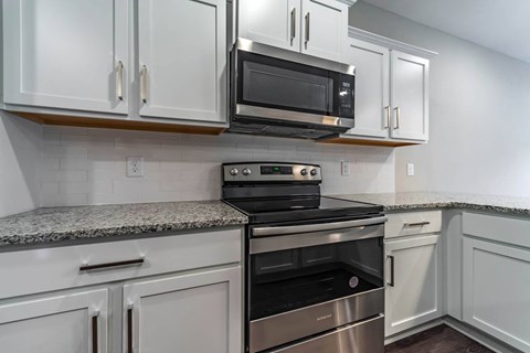 A kitchen with white cabinets and a granite countertop.