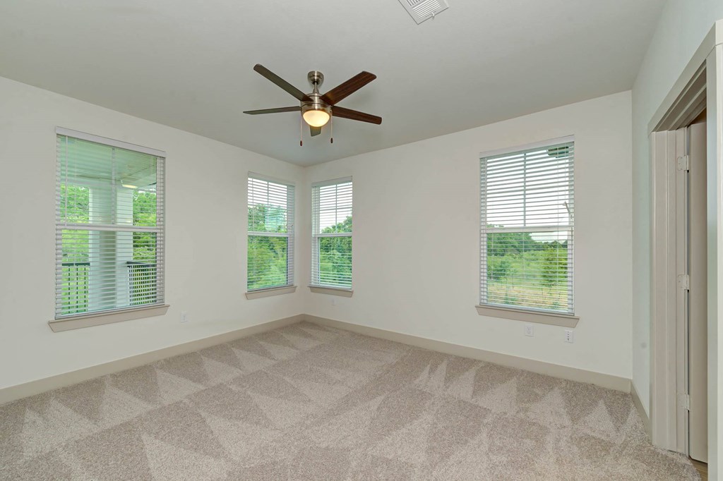 an empty living room with a ceiling fan and three windows at Legacy at Cibolo, Boerne, TX