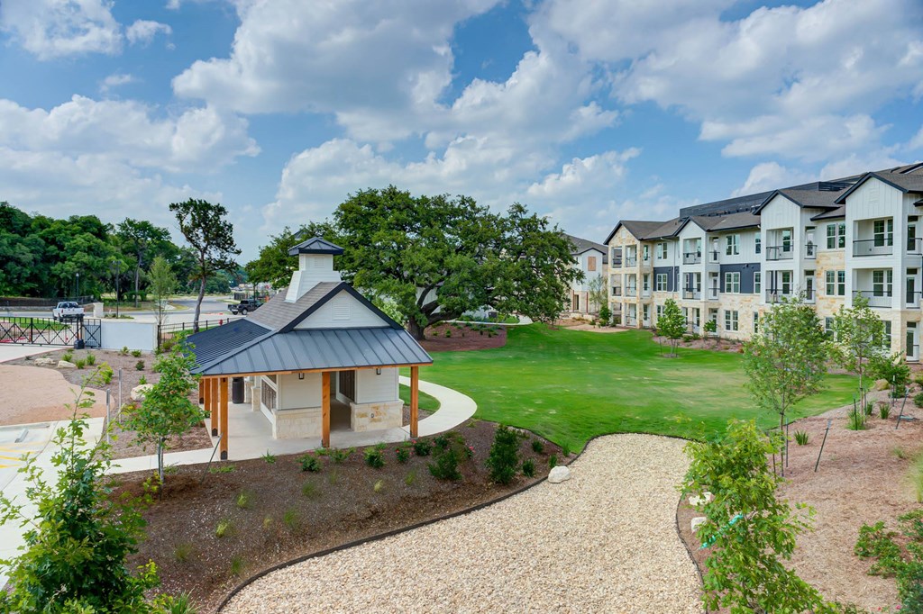an exterior view of an apartment building with a green lawn and a pathway at Legacy at Cibolo, Texas