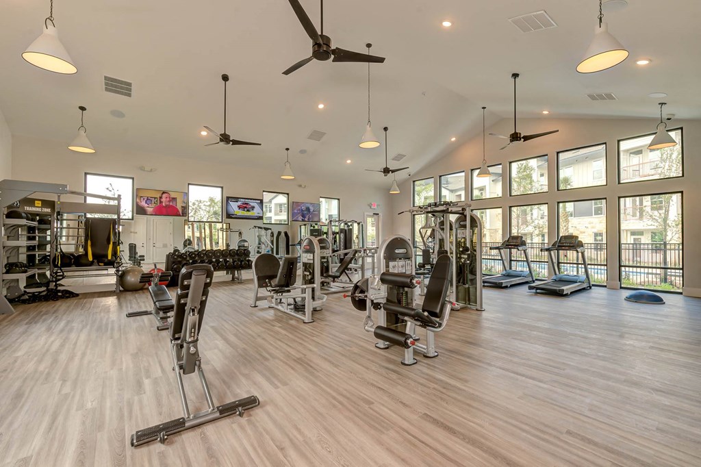 a gym with weights and cardio equipment and windows at Legacy at Cibolo, Boerne, TX