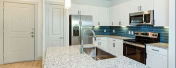 a kitchen with granite counter tops and a stainless steel refrigerator at Legacy at Cibolo, Texas