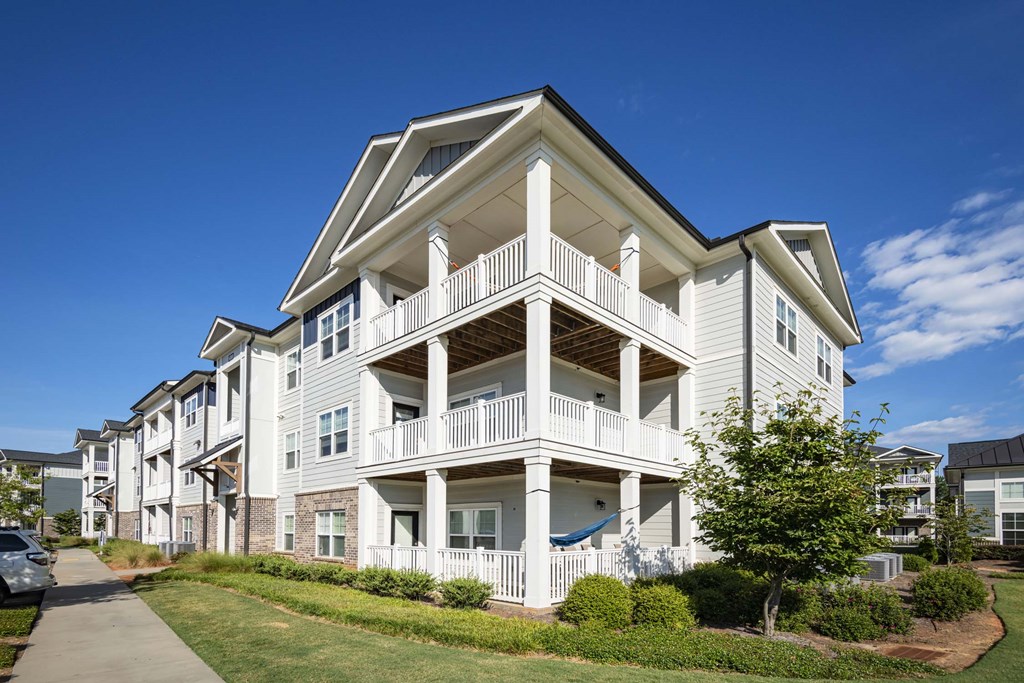 A white two-story apartment building with a balcony on the second floor at Waterleaf at Neely Ferry Apartments, South Carolina