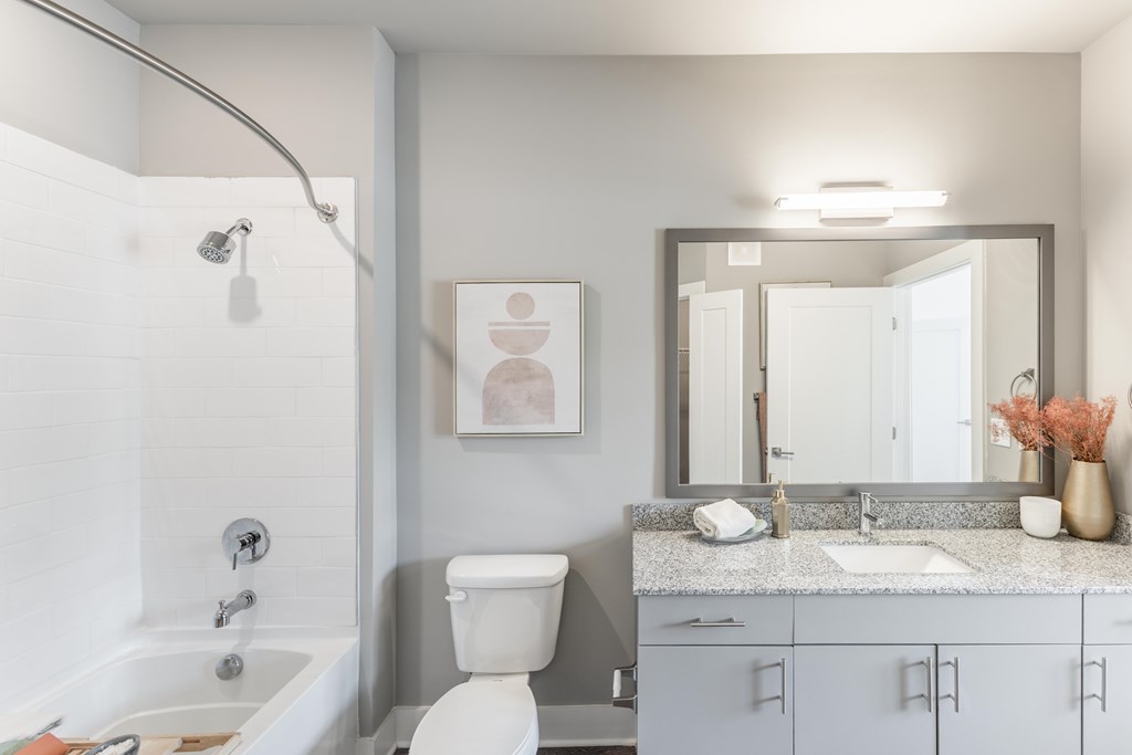 White tiled bathroom with a white bathtub, sink, and a white shower head at Prosper Madison Oaks, Madison