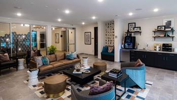 A living room with a brown couch, a coffee table, and a blue chair at Hudson at Renaissance Apartments, Wilmington, NC 28405