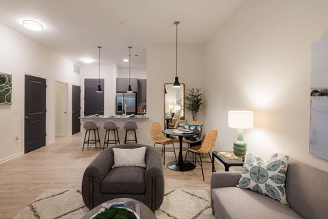 A living room with a grey couch, a coffee table, and a dining table with chairs.