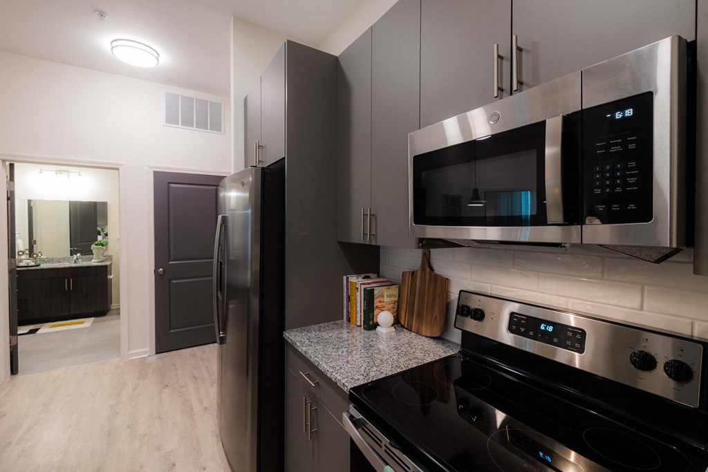 A modern kitchen with a black refrigerator and stainless steel appliances at Hudson at Renaissance Apartments, North Carolina 28405
