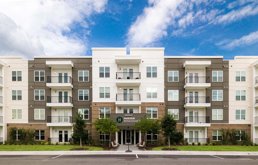 A large apartment complex with a green lawn in front at Hudson at Renaissance Apartments, Wilmington 28405