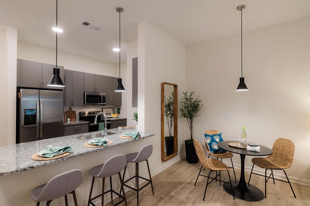 A kitchen with a bar area and a dining table with chairs at Hudson at Renaissance Apartments, Wilmington, NC