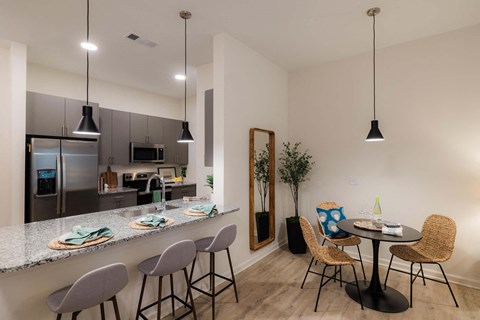 A kitchen with a bar area and a dining table with chairs.