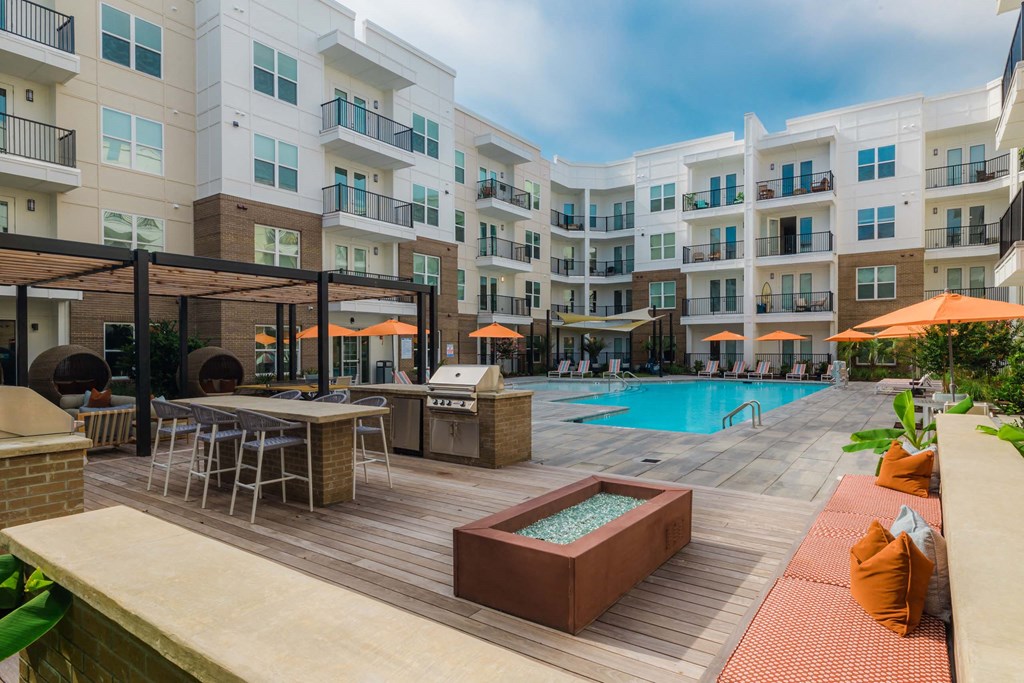 A large outdoor pool area with a hot tub and lounge chairs at Hudson at Renaissance Apartments, Wilmington, NC