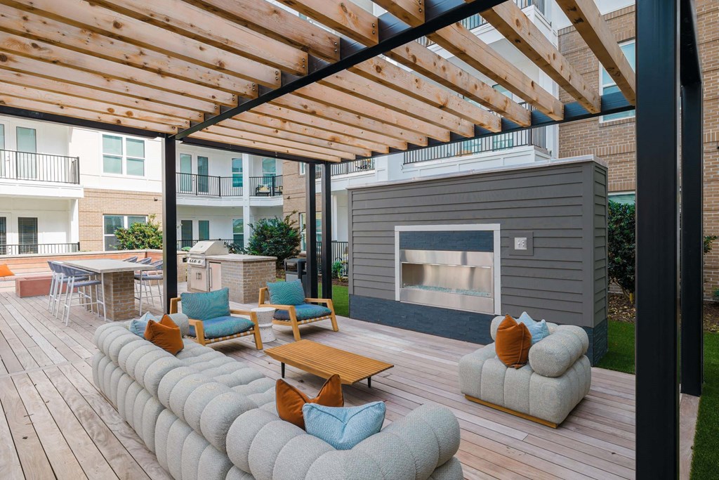 A wooden deck with a fireplace and seating area at Hudson at Renaissance Apartments, Wilmington, NC