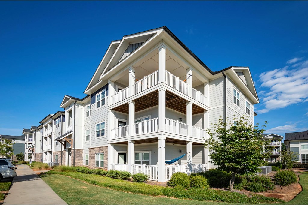 A white two-story apartment building with a balcony on the second floor at Waterleaf at Neely Ferry Apartments, Simpsonville