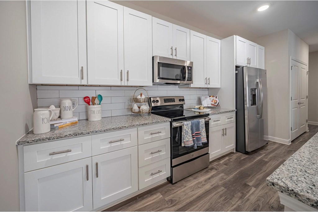 A kitchen with white cabinets and a granite countertop at Waterleaf at Neely Ferry Apartments, Simpsonville, SC