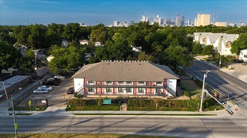 A building with a red roof is surrounded by trees and a parking lot.