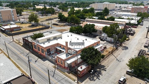 A large building with a red brick exterior sits in the middle of a parking lot.