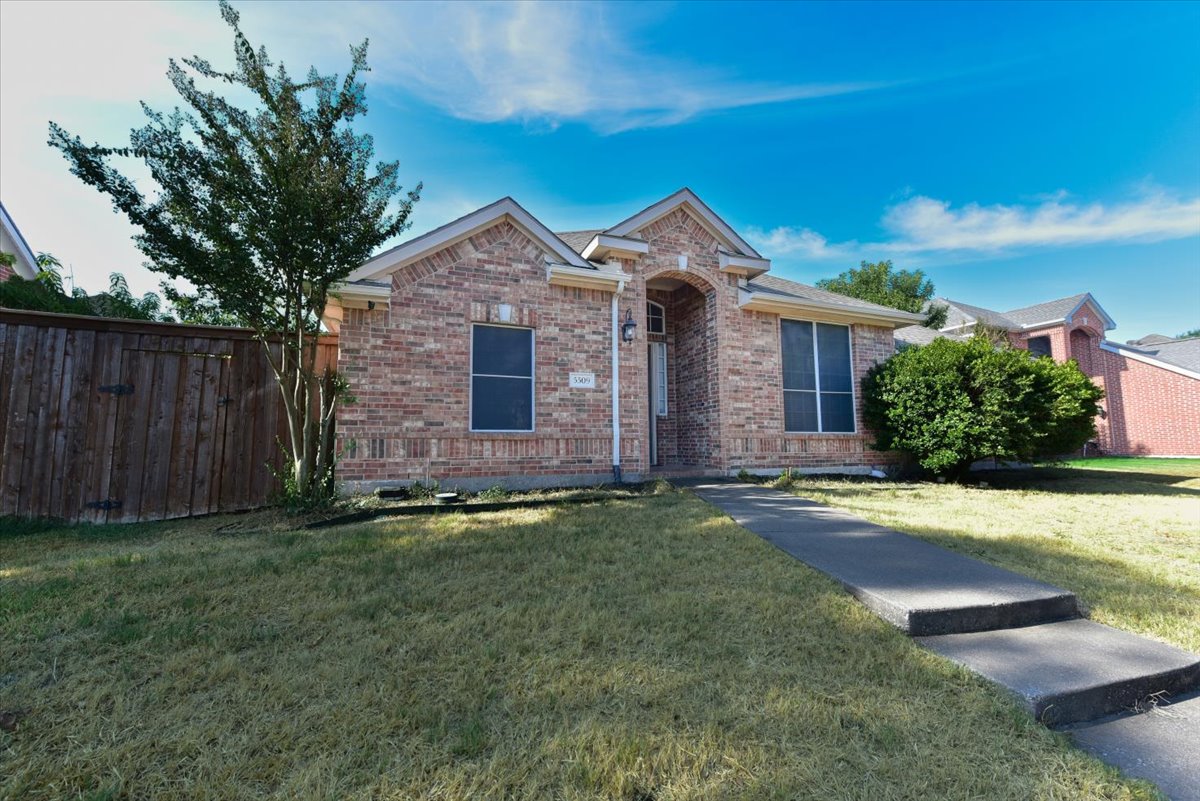 A house with a brick facade and a tree in front.