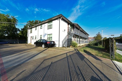 A black car is parked in front of a white building.