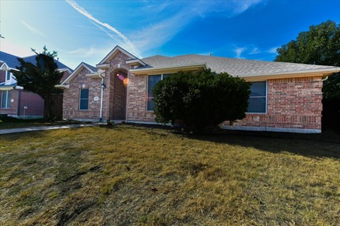 A house with a red brick exterior and a large front yard.