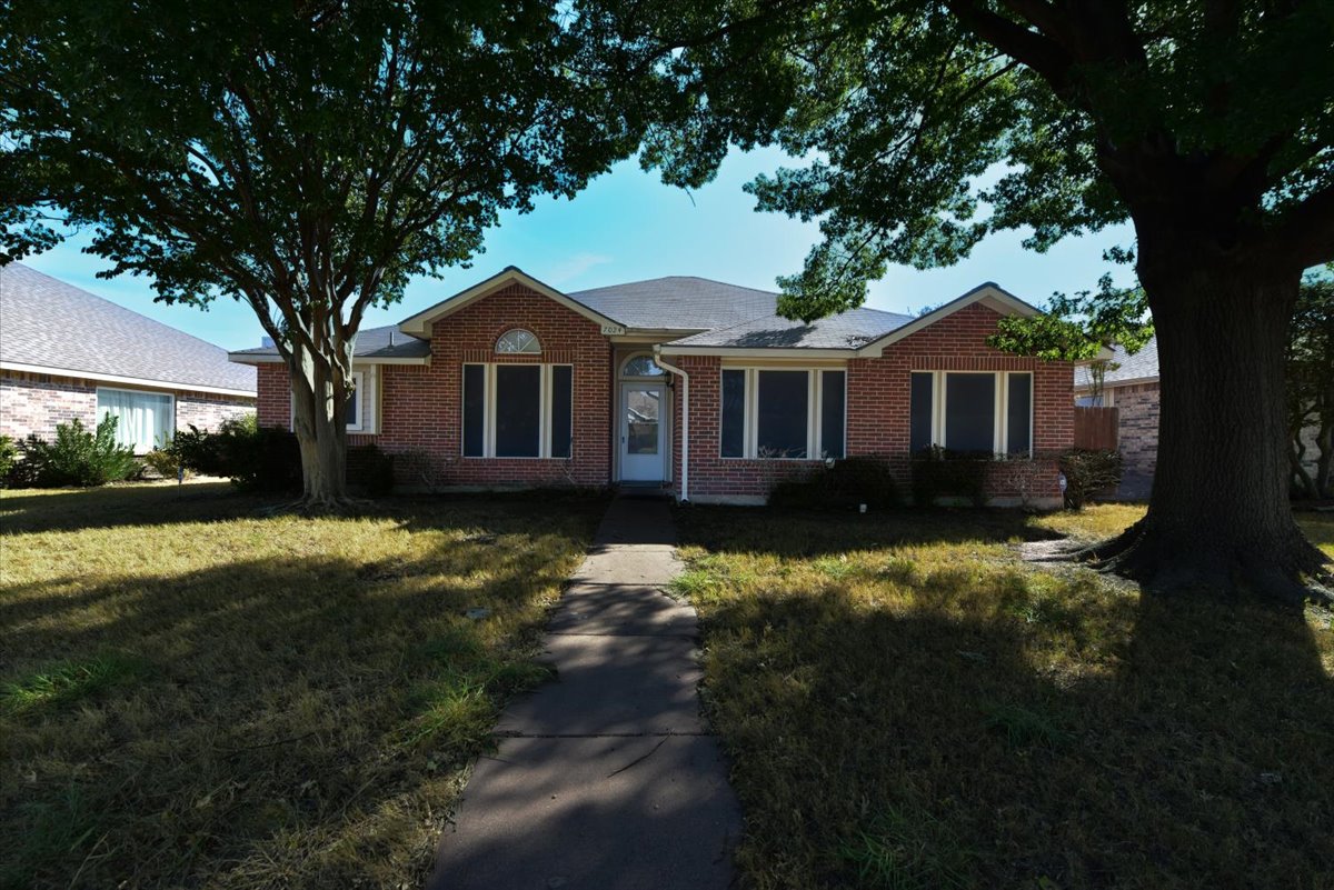 A house with a white door and windows surrounded by trees.