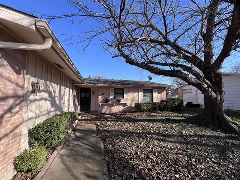 A tree with no leaves stands in front of a house.