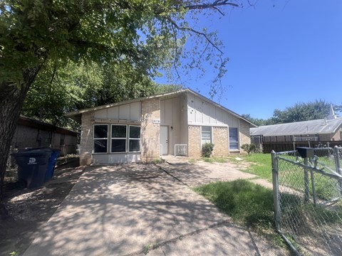A house with a driveway and a fence in front.