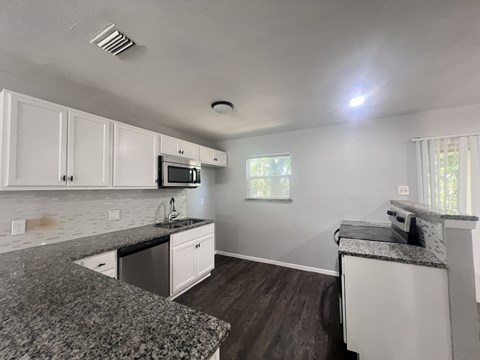 A kitchen with a granite countertop and white cabinets.