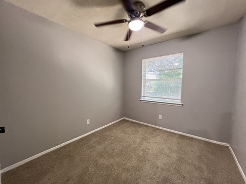 A room with a ceiling fan and a window.