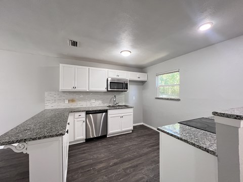 A kitchen with white cabinets and a granite countertop.