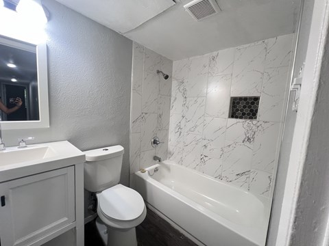 A white bathroom with a marble tile shower.