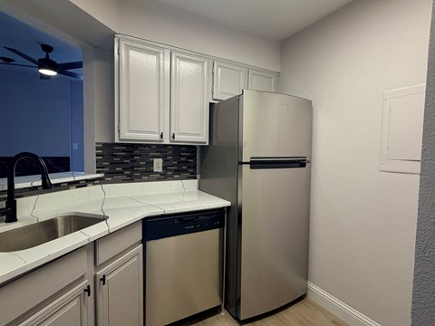 A kitchen with a stainless steel refrigerator and white cabinets.