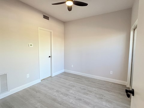 A room with a ceiling fan and a door.