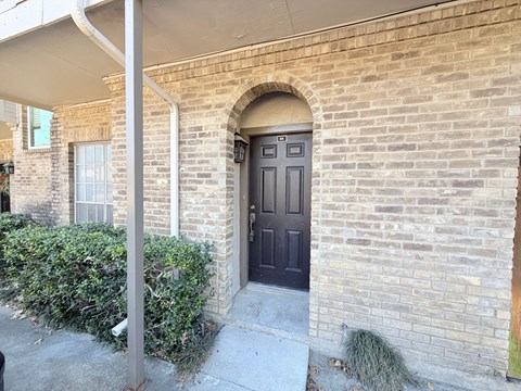 A house with a brown door and a grey wall.